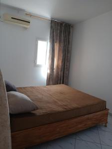 un letto in una stanza con una finestra e una struttura del letto di Appartement Anne Djerba Phare a Al Maqārisah Altre 2 foto