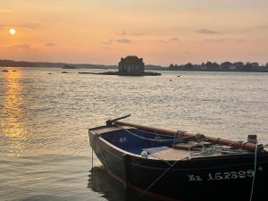 a boat in the water with a house in the background at Gîtes d Izel2 entre terre et mer prés d'un golf in Ploemel