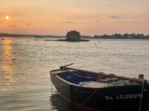a boat in the water with a house in the background at Gîtes d Izel N1 entre terre et mer prés d'un golf in Ploemel