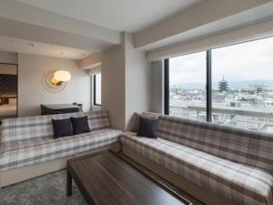 a living room with two couches and a large window at Loisir Hotel Kyoto Toji in Kyoto