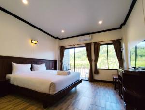 Un dormitorio con una cama, un escritorio y ventanas. en Golden sand khaolak Resort, en Khao Lak