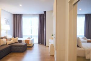 una sala de estar con un sofá y una cama en THE KANNAS Hotel & Serviced Apartment, Chiang Mai SHA Certified, en Chiang Mai