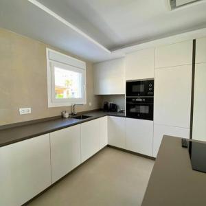 a large kitchen with white cabinets and a window at MAR y CALMA NG in Benicarló