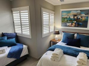 a bedroom with two beds with blue pillows and windows at Frinton on Sea 12 in Ballito