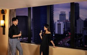 a man and a woman standing in front of a window at Mandarin Oriental, Jakarta in Jakarta