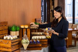 a woman holding a plate of food in a restaurant at Mandarin Oriental, Jakarta in Jakarta