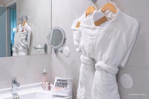a bathroom with white robes hanging in front of a sink at Aparthotel AMMI Nice Lafayette in Nice
