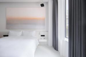a white bedroom with a bed and a window at Shenzhen INNOGYM Hotel in Shenzhen