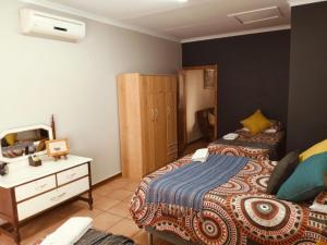 a bedroom with two beds and a dresser in it at Anri Guesthouse in Bloemfontein