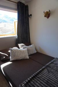 1 cama con 2 almohadas en una habitación con ventana en VA THORENS studio SUD VUE 180 WIFI, en Val Thorens