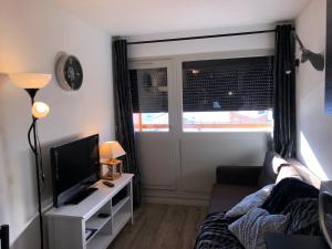 Una sala de estar con un sofá y un televisor. en VA THORENS studio SUD VUE 180 WIFI, en Val Thorens