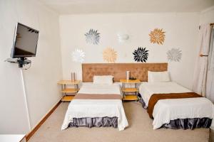 a room with two beds and a flat screen tv at Crystal Palace Hotel in Gaborone