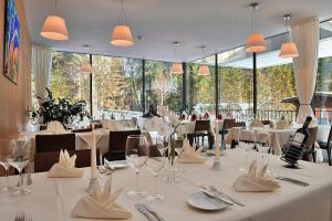 ロイテにあるAlpenhotel Ammerwaldの白いテーブルと椅子、大きな窓のあるレストラン