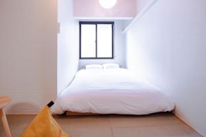 Kyōtoにあるゲストハウス愛の家 Guesthouse Ainoieの白いベッドと窓のある寝室