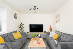 a living room with a couch and a tv at Peak District New Modern Cottage with Mountain Views in Buxton