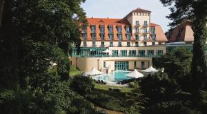 ein Hotel mit einem Swimmingpool vor einem Gebäude in der Unterkunft Precise Resort Scharmützelsee - Golf & SPA in Bad Saarow