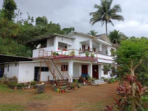 a white house with a staircase in front of it at Royal Valley Apartment in Kalpetta