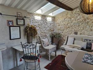ein Wohnzimmer mit einer Steinmauer mit einem Tisch und Stühlen in der Unterkunft Le Mas Saint Pierre in Roquefort-les-Pins + 23 Fotos