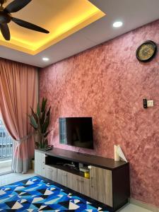 ein Wohnzimmer mit einem TV und einer roten Wand in der Unterkunft Pink Castle Adelia Bangi Avenue in Kampong Batu Lima Bangi