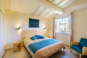 a bedroom with a large bed and a blue chair at Villa des Cigales vue mer avec piscine/proche plage in Grimaud +22 photos