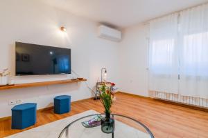 a room with a tv and a table with a vase of flowers at Peaceful Nest In City Center - Happy Rentals in Zagreb