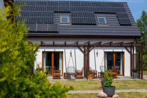 a house with a pitched roof with a porch at Apartamenty Nadmorska Osada in Łeba