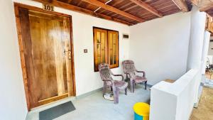 a room with two chairs and a wooden door at Arugam Bay Holiday in Arugam Bay