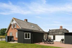 a house with a black roof and chairs in a yard at Lovely House By The Water With Cozy Courtyard in Thyholm