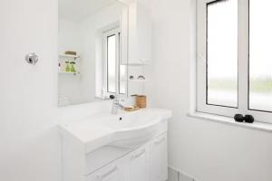 a white bathroom with a sink and a window at Lovely House By The Water With Cozy Courtyard in Thyholm +18 photos