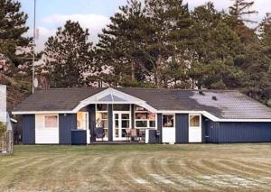a blue and white building with trees in the background at Summerhouse On The Beach And With Ocean View in Yderby
