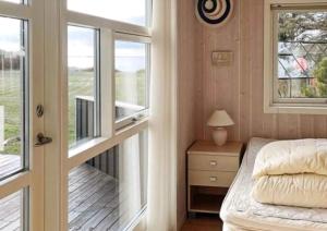 a bedroom with a bed and a balcony with a window at Summerhouse On The Beach And With Ocean View in Yderby
