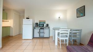 a kitchen with a table and a white refrigerator at Samaria Village N08 - 2P4 in Agde +4 photos