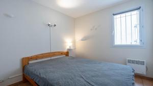 a white bedroom with a bed and a window at Samaria Village N08 - 2P4 in Agde