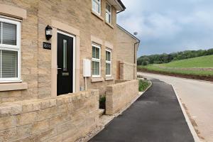a brick house with a black door and a driveway at Peak District New Modern Cottage with Mountain Views in Buxton