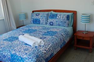 a bed with blue and white sheets and two lamps at Affordable full house for family and pet friendly in Taperoo