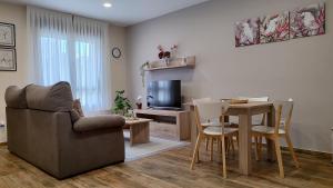 a living room with a couch and a table and a television at APARTAMENTOS TURISTICOS LAS CANDELAS in Puebla de Sanabria