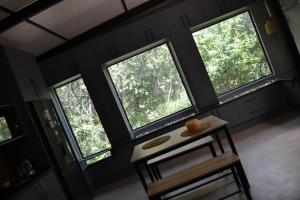 a room with three windows and a chair and a table at Klein Eden Forest in Rustenburg