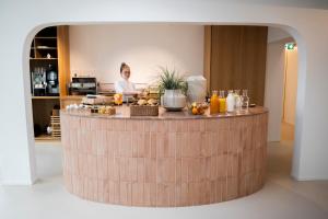 菲尔德施塔特Das Kaya Hotel Stuttgart Airport Messe的站在柜台后面的人,上面有水果