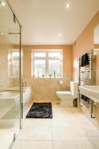 a bathroom with a tub and a toilet and a sink at Entire 4-Bedroom Home Surrey in Sunbury Common