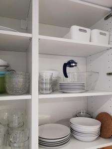 a white pantry with plates and bowls on shelves at SmartApart - Design Apartment - Favorite Place - Full Equipment - Public Transport in Nürnberg +25 photos
