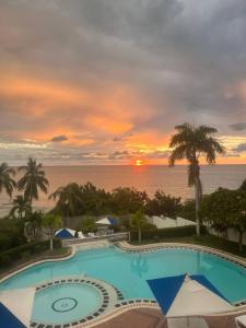 ein Resortpool mit Sonnenuntergang im Hintergrund in der Unterkunft Unwind in Santa Martas Oceanfront Retreat in Playa Dormida