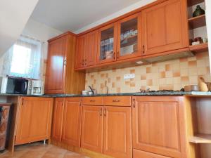 Una cocina con gabinetes de madera y microondas. en Hegy és Balaton Vendégház, en Badacsonytördemic