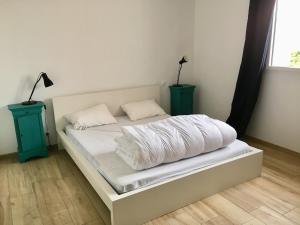 a bed with white sheets and two night stands at La Vigie in Crozon +3 photos