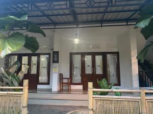 a house with a porch with doors and a chair at Sri Sedana Guest House in Sidemen