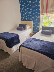 two beds in a room with a blue wall at House in central winchester in Winchester