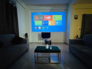 Una gran pantalla en la sala de estar con sofá y mesa. en Netflix & Chill Projector Penthouse in Kondapur, en Kondapur