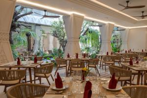a dining room with tables and chairs and trees at La Plante Siem Reap in Siem Reap