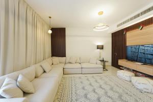 a living room with a white couch and a television at Modern Villa Stay Private & Secure Damac Hills 2 in Dubai +14 photos