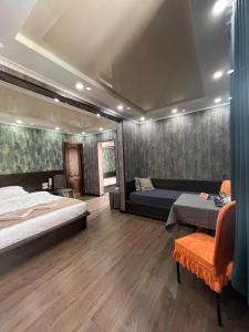 比什凯克Salut Hotel的一间卧室，里面有一张床、一张沙发和一张桌子