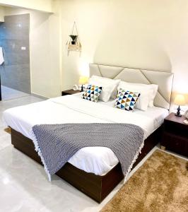 パンチガニにあるLakewood Bohemian Home In Panchganiの白いシーツと枕が付いた大きなベッドのある寝室
